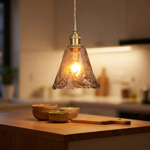 Suspension rétro en verre ambré au-dessus d'un îlot de cuisine avec lumière chaude