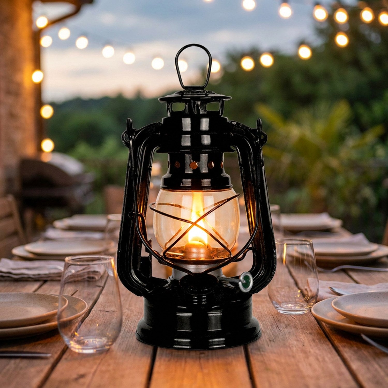 Lanterne à pétrole allumée au centre d'une table de dîner dressée sur une terrasse d'été
