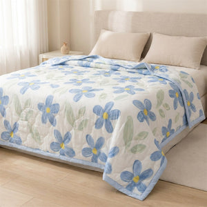 Couette d'été à fleurs bleues dépliée sur un grand lit dans une chambre chaleureuse