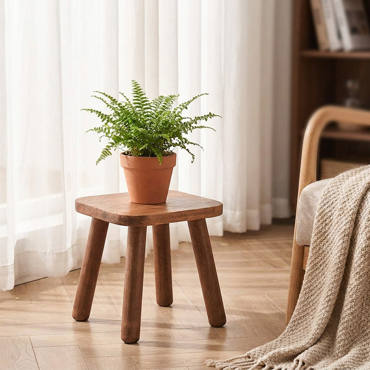 Tabouret en bois massif utilisé comme sellette avec une plante verte près d'une fenêtre