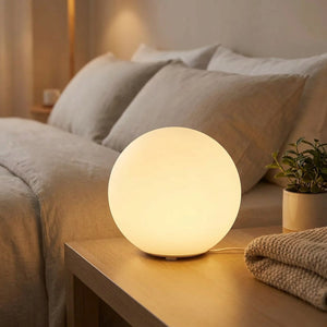 Lampe boule allumée sur une table de chevet dans une chambre cosy