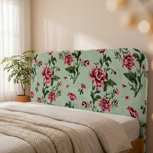 Tête de lit habillée d'une housse velours à roses dans une chambre lumineuse avec plante verte et voilage