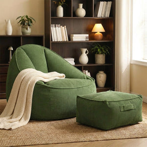 Fauteuil pouf vert et repose-pieds assorti près d'une bibliothèque