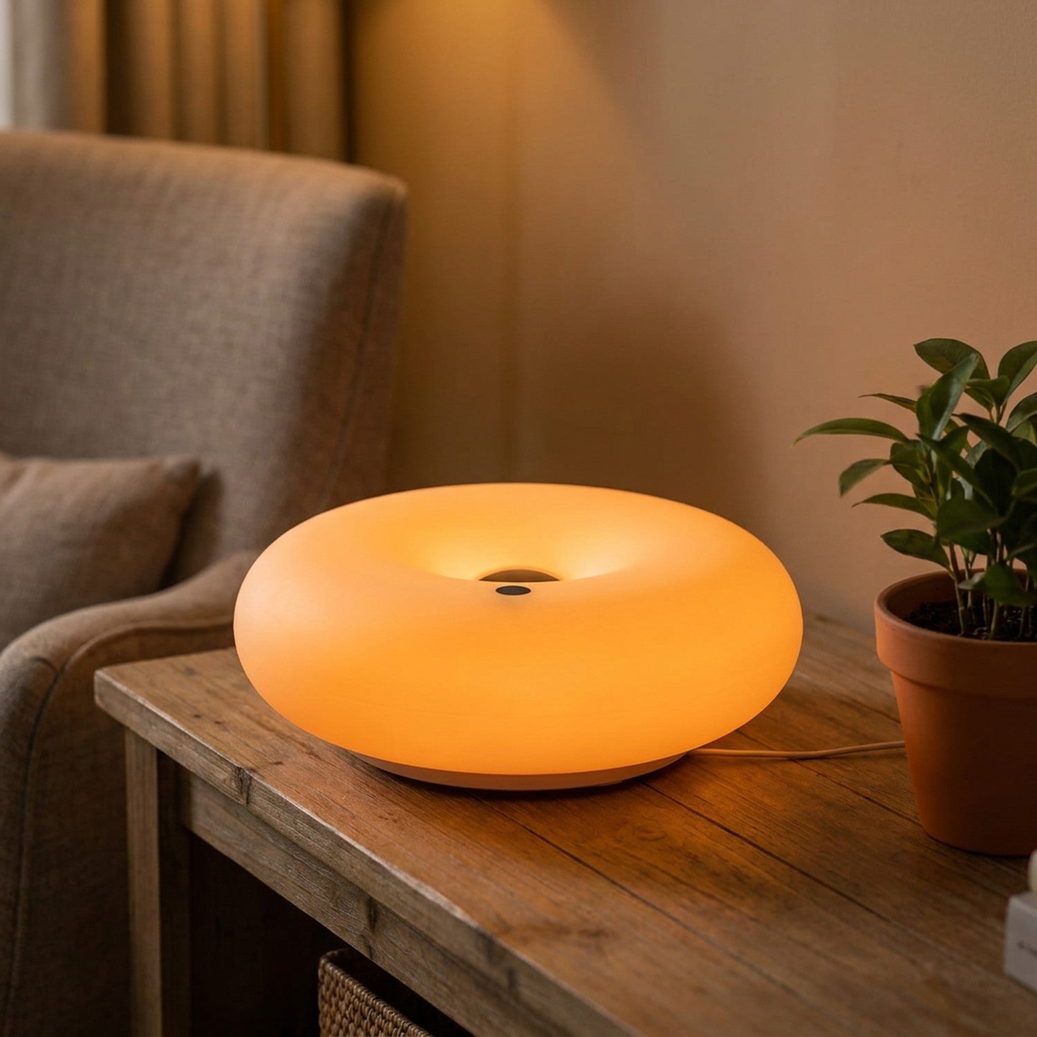 Lampe beignet Bauhaus allumée en orange dans un salon près d'une plante