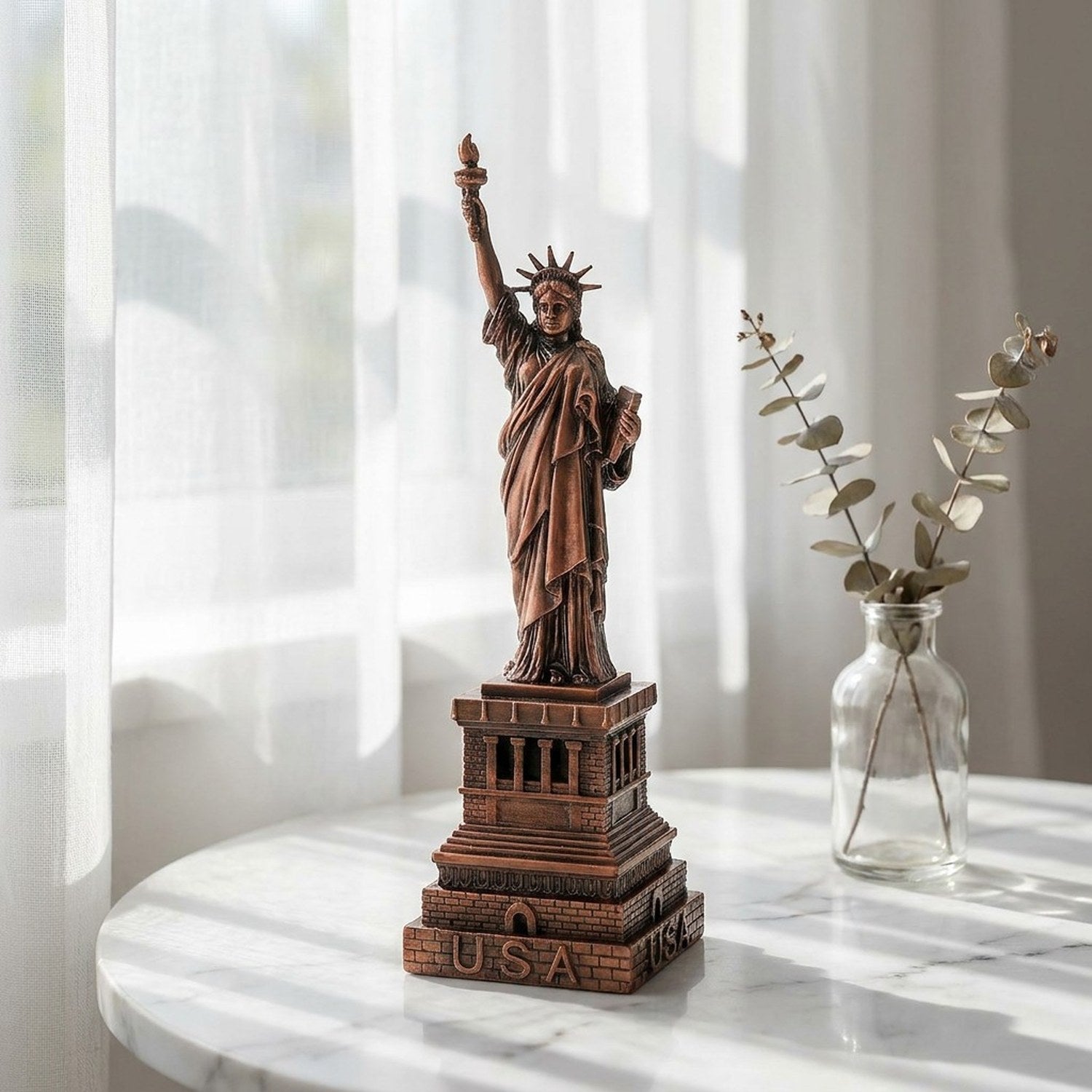 Statuette de la Liberté en métal bronze sur surface en marbre avec rideau voilage et branche d'eucalyptus
