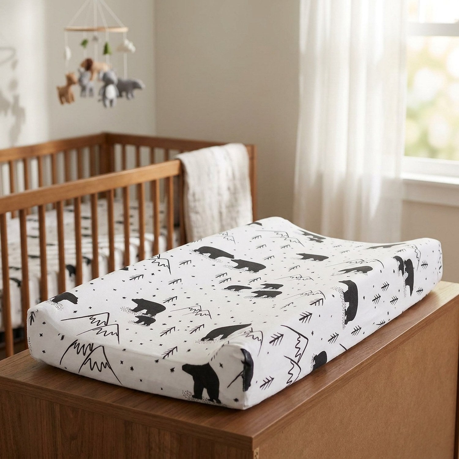 Housse de matelas à langer motif ours dans une chambre de bébé avec berceau en bois