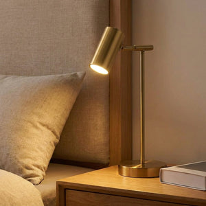 Lampe de bureau dorée allumée sur une table de chevet dans une chambre chaleureuse