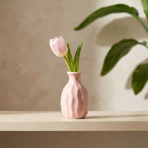 Vase soliflore côtelé rose avec une tulipe sur une étagère claire