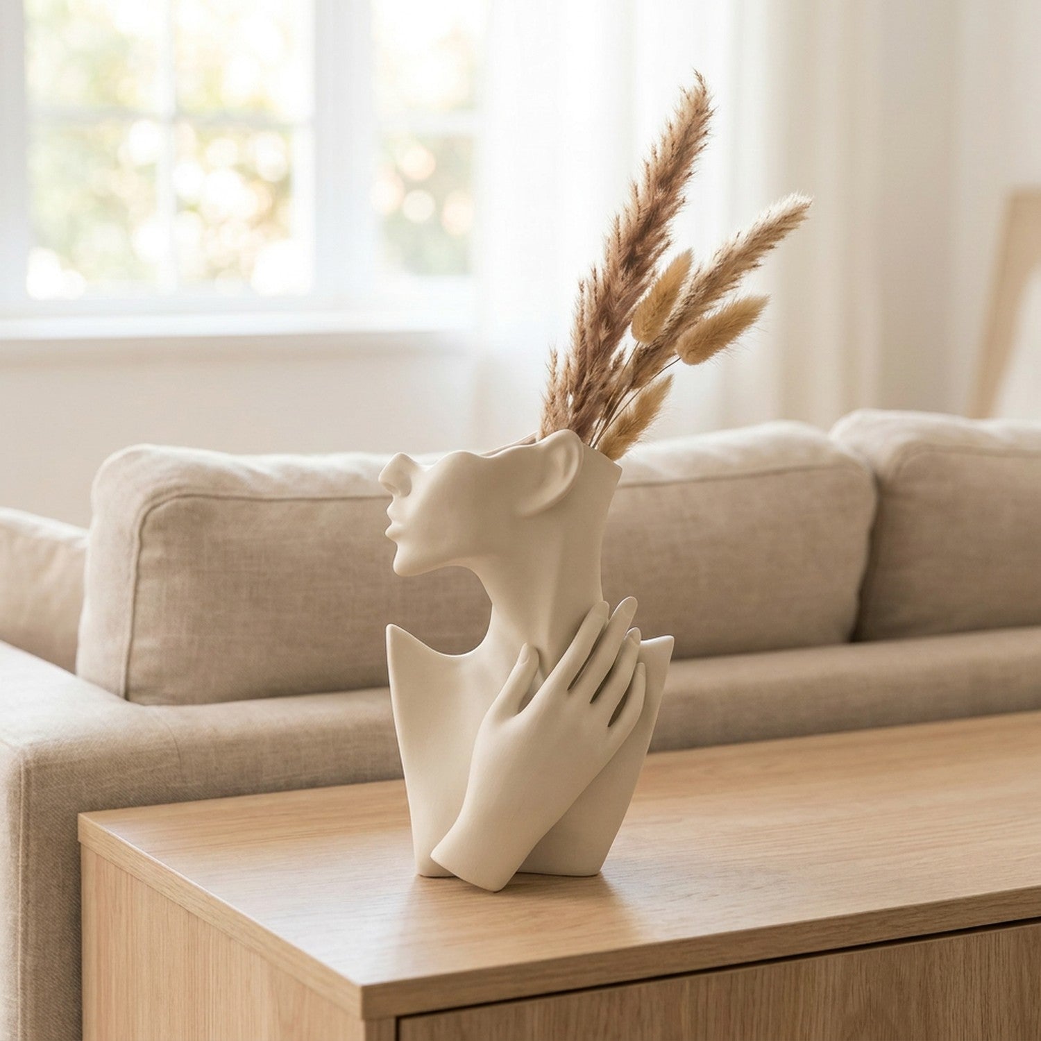 Vase visage en céramique blanche posé sur une console dans un salon lumineux avec des pampas