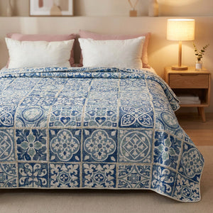 Couvre-lit matelassé bleu sur un lit dans une chambre moderne avec lampe de chevet allumée