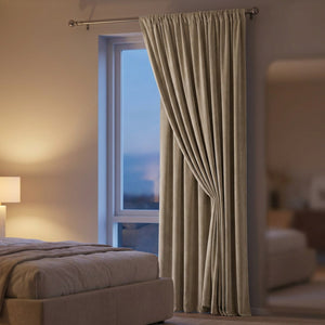 Rideau occultant en velours beige dans une chambre en soirée avec lampe allumée