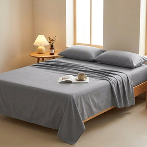 Drap plat gris installé sur un lit avec livre et tasse de café pour un moment de lecture