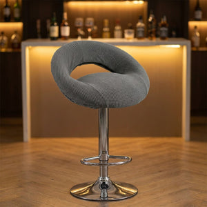 Housse de tabouret de bar demi-lune grise sur un tabouret devant un bar chaleureux