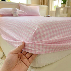 Coin élastiqué du drap-housse à carreaux rose tendu sur le matelas