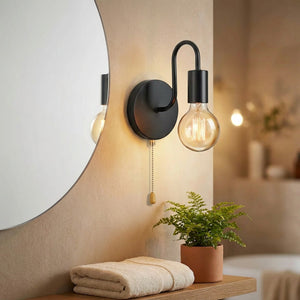 Applique murale noire allumée à côté d'un miroir rond dans une salle de bain