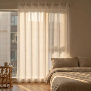 Voilage blanc rayé dans une chambre baignée de lumière dorée du matin