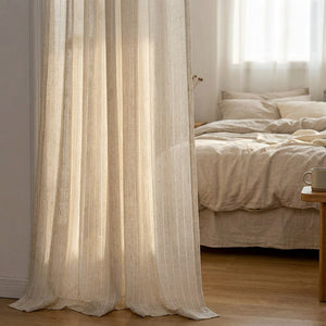 Voilage beige tamisant devant une fenêtre de chambre à coucher