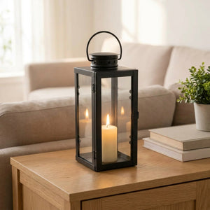 Lanterne à bougie en métal noir posée sur une console dans un salon lumineux