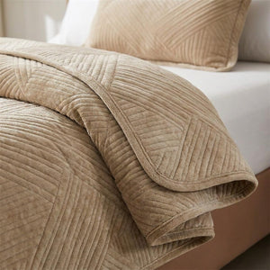 Gros plan sur le velours pelucheux et le motif géométrique brodé du couvre-lit matelassé