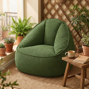 Fauteuil pouf vert en velours côtelé installé sur un balcon avec plantes
