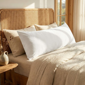 Housse de coussin en velours blanc sur un lit avec tete de lit en rotin