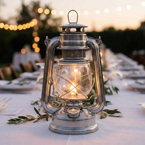 Lanterne tempête posée sur une table de mariage en extérieur avec guirlande lumineuse