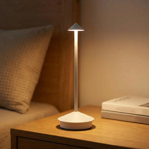 Lampe de table blanche allumée sur une table de chevet dans une chambre