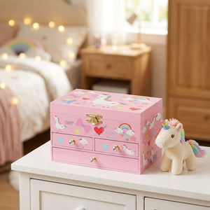 Boîte à musique licorne arc-en-ciel fermée posée près d'une peluche licorne