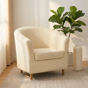 Fauteuil club en housse écru à côté d'une bibliothèque en bois et d'une plante verte