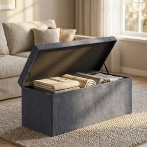 Banc coffre en velours gris ouvert montrant le rangement intérieur avec couvertures