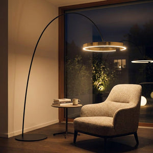 Lampadaire arc doré allumé près d'un fauteuil de lecture cosy le soir