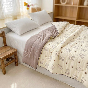 Couette légère à motif petits ours sur un lit dans une chambre enfant avec petite chaise en bois
