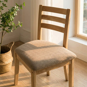 Housse de siège de chaise beige sur une chaise en bois près d'une fenêtre avec une plante