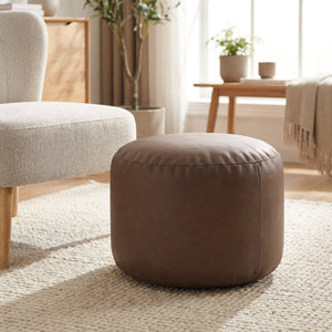 Pouf ottoman rond en simili cuir marron café en assise d appoint près d un fauteuil