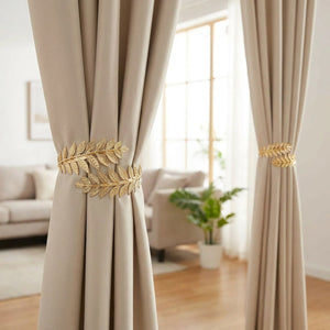 Deux embrasses dorées à feuilles retenant des rideaux beiges dans un salon lumineux