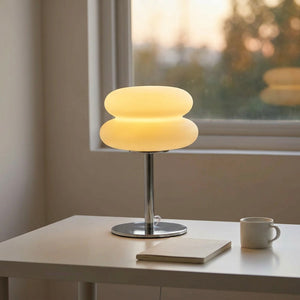 Lampe de chevet champignon allumée sur un bureau blanc près d'une fenêtre au coucher du soleil