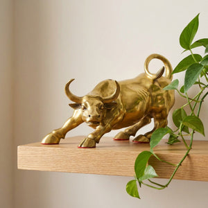 Statue taureau doré sur une étagère murale en chêne avec une plante verte