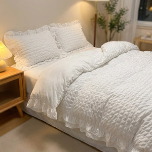 Parure de lit blanche dans une chambre moderne avec table de chevet et lampe chaleureuse