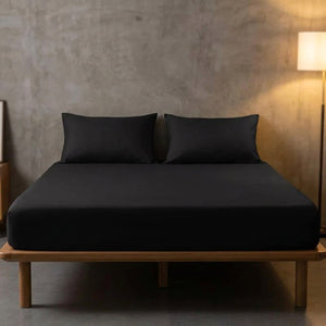 Drap housse noir sur un lit dans une chambre au mur en béton avec lampadaire