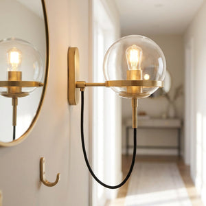 Applique murale boule de verre dorée près d'un miroir dans une entrée chaleureuse