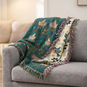 Plaid plié sur canapé gris avec franges à pompons