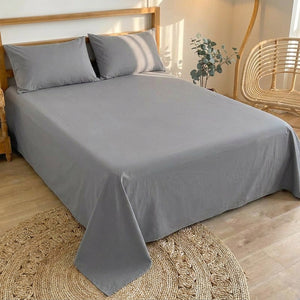 Drap plat gris sur un lit dans une chambre moderne avec fauteuil en rotin
