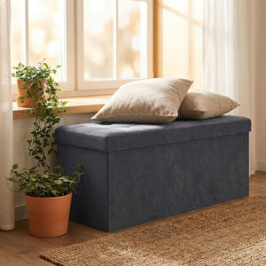 Banc de rangement en velours gris sous une fenêtre avec deux coussins