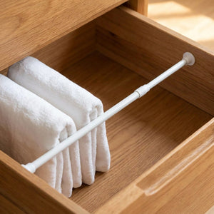 Tringle blanche fine dans un tiroir servant de séparateur pour serviettes pliées