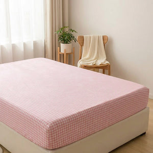 Drap-housse à carreaux rose dans une chambre lumineuse avec plante et plaid