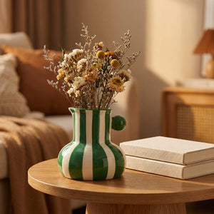 Vase rayé vert sur une table d appoint avec un bouquet de fleurs séchées à la lumière dorée