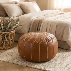 Pouf marocain marron au pied d'un lit dans une chambre aux tons naturels