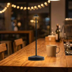 Lampe de table noire allumée sur un comptoir de café le soir