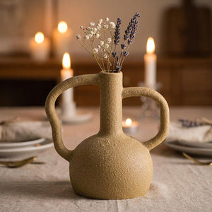 Vase en céramique beige au centre d'une table avec fleurs séchées