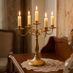 Gros plan sur le chandelier doré et ses bougies allumées sur une console ancienne